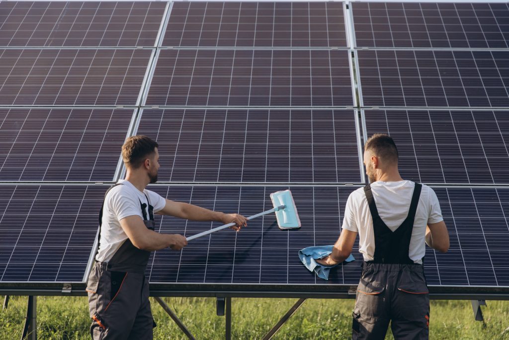 2 männer die mit einem wischmob eine solaranlage reinigen