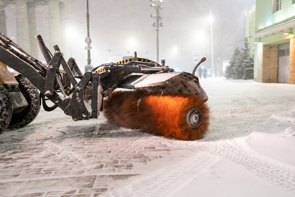 Kehrmaschine zur Schneeräumung der Bürgersteig in einer winterlichen Stadt reinigt